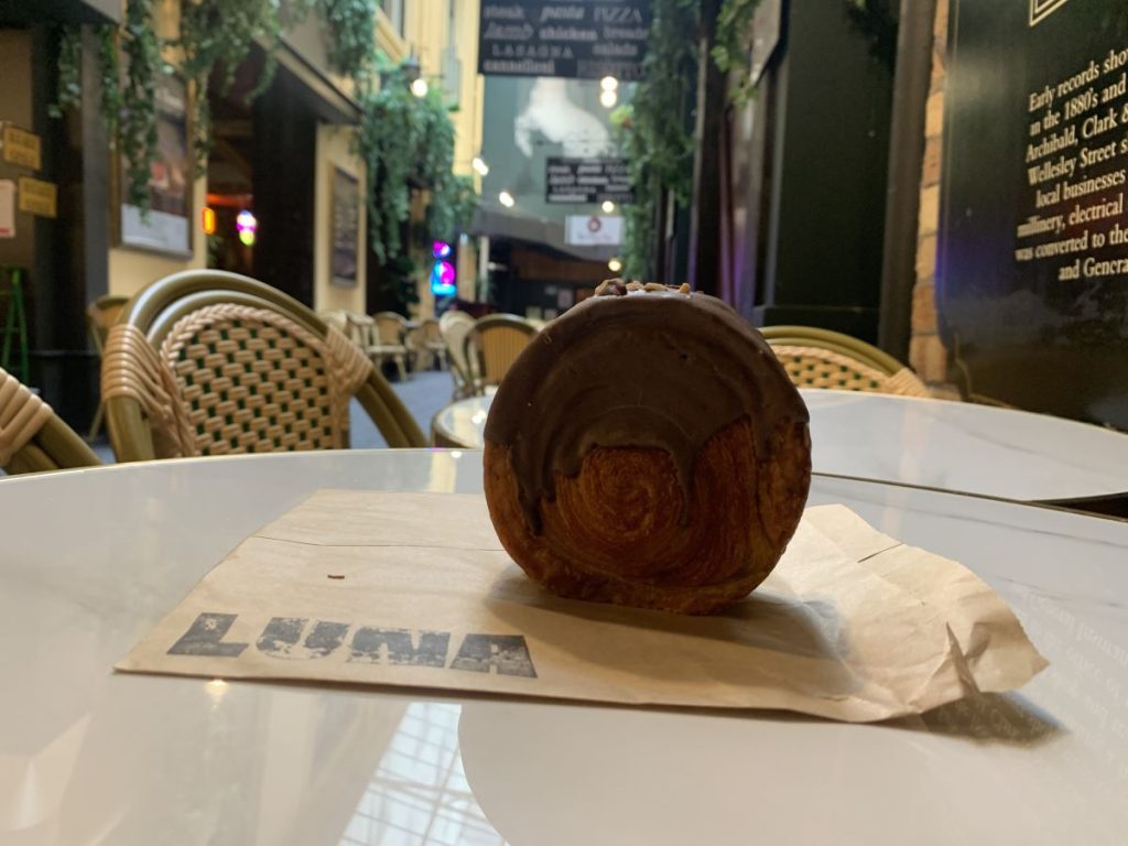 Large round croissant dipped in chocolate photographed on a table at Elliot Stables, Auckland.