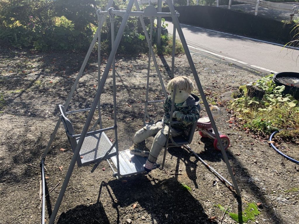 Scarecrow of a child sits on a swing in Scarecrow Village