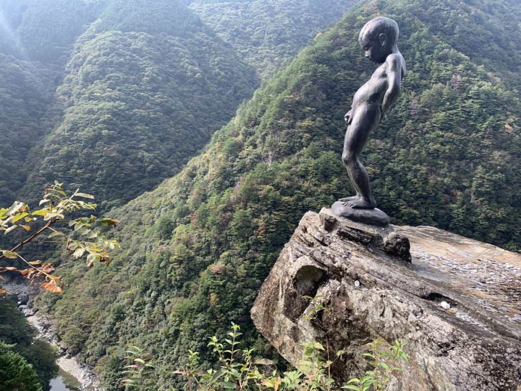 Statue of a small child peeing into a gorge in the Iya Valley, Japan