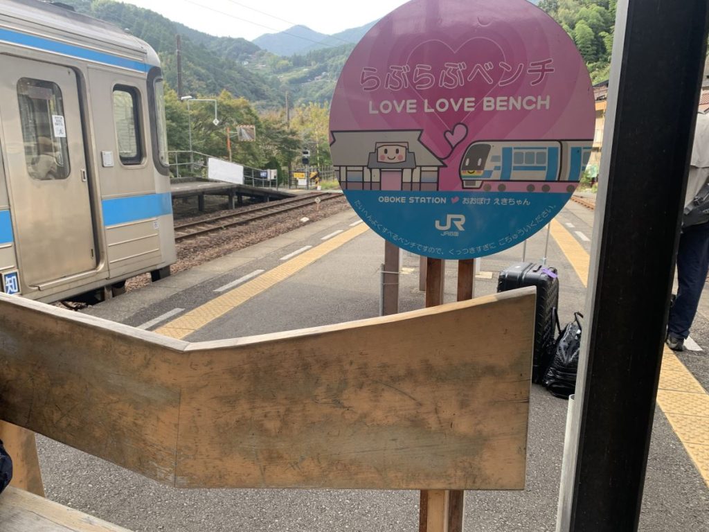 The Love Love Bench sign at Oboke Station, Japan - the back of the bench dips in the middle so couples can sit together