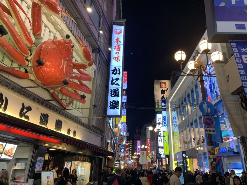 View down Dotonbori at night showing the lit up signs - the giant crab outside Kani Doraku is in the front of the picture