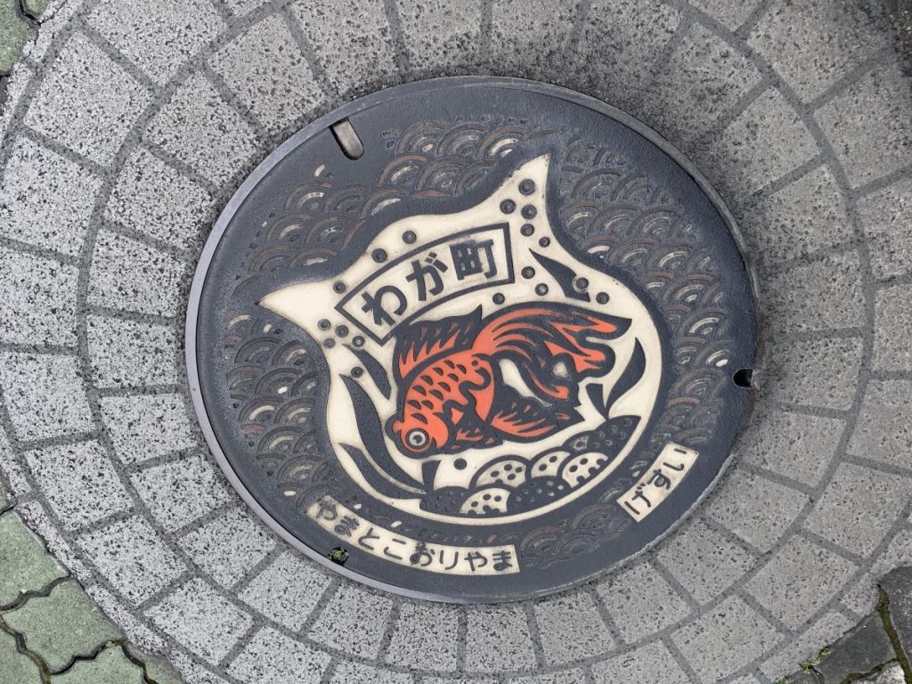 Manhold cover with a red goldfish on top in the Goldfish town near Nara