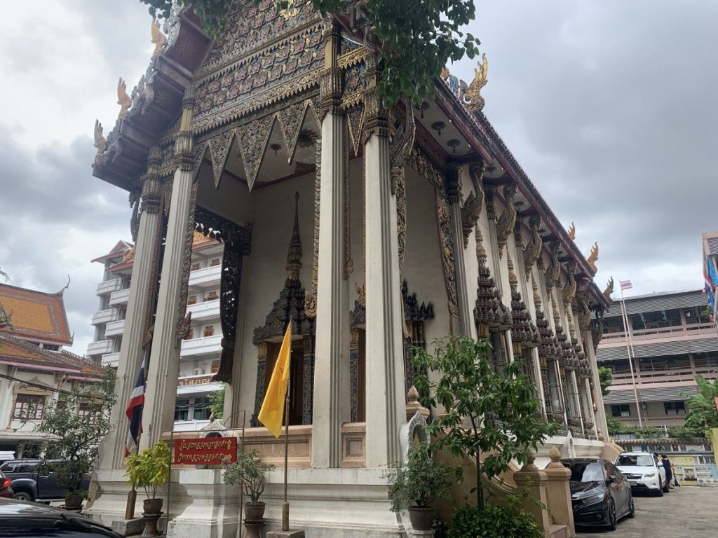 Exterior of Wat Khanikaphon. With an ornate carved roof and stone pillars at the front.