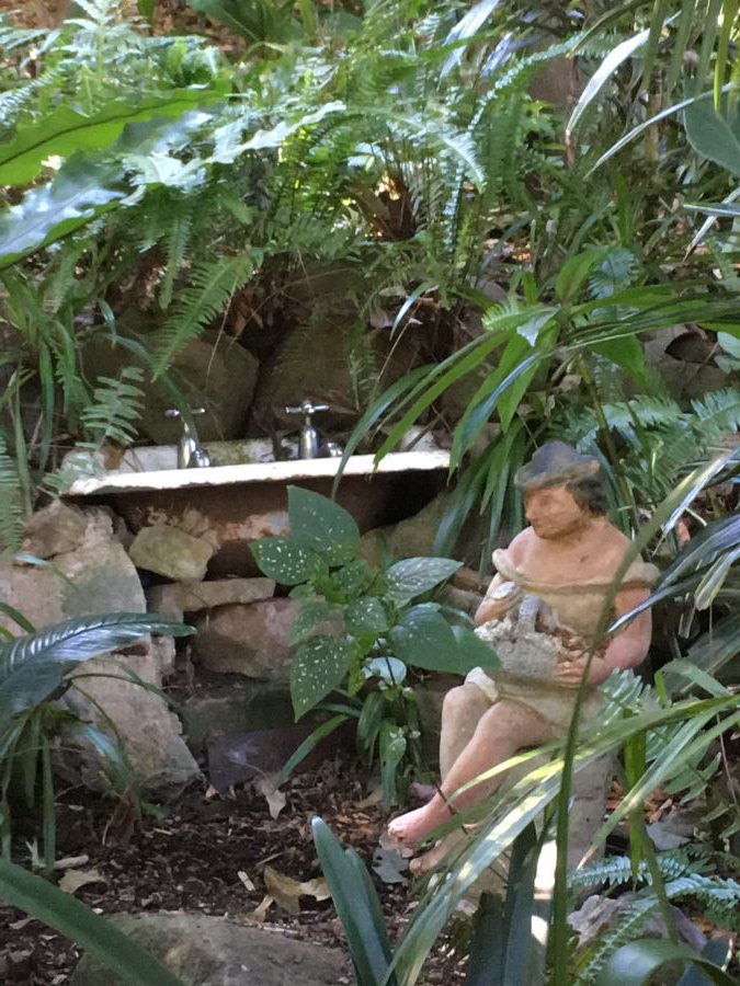 A small sink and a model figure hiden in foliage at Wendy's Secret Garden, Sydney