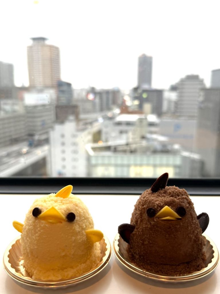 A yellow vanilla chick cake and a brown chocolate one sit side by side on a windowsill in Nagoya